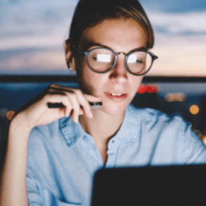 woman working on laptop with coastal sunset in background