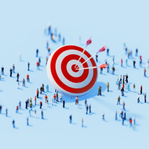 Large red and white bullseye target standing upright on a light blue surface. Three arrows are hit directly in the center of the target, while numerous tiny, miniature figures of people are scattered all around it.
