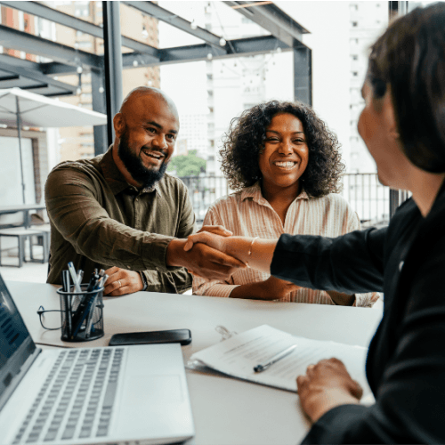 Financial professional shakes hands with a smiling client during a successful consultation meeting.