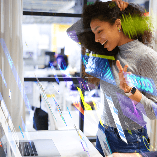 Person smiling while interacting with digital graphics on a transparent display in a modern office.