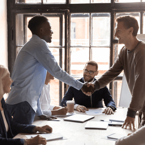 Two business colleagues shaking hands during a meeting, building a partnership to reach HR decision-makers.
